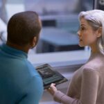 A woman holding a tablet with a man looking at it